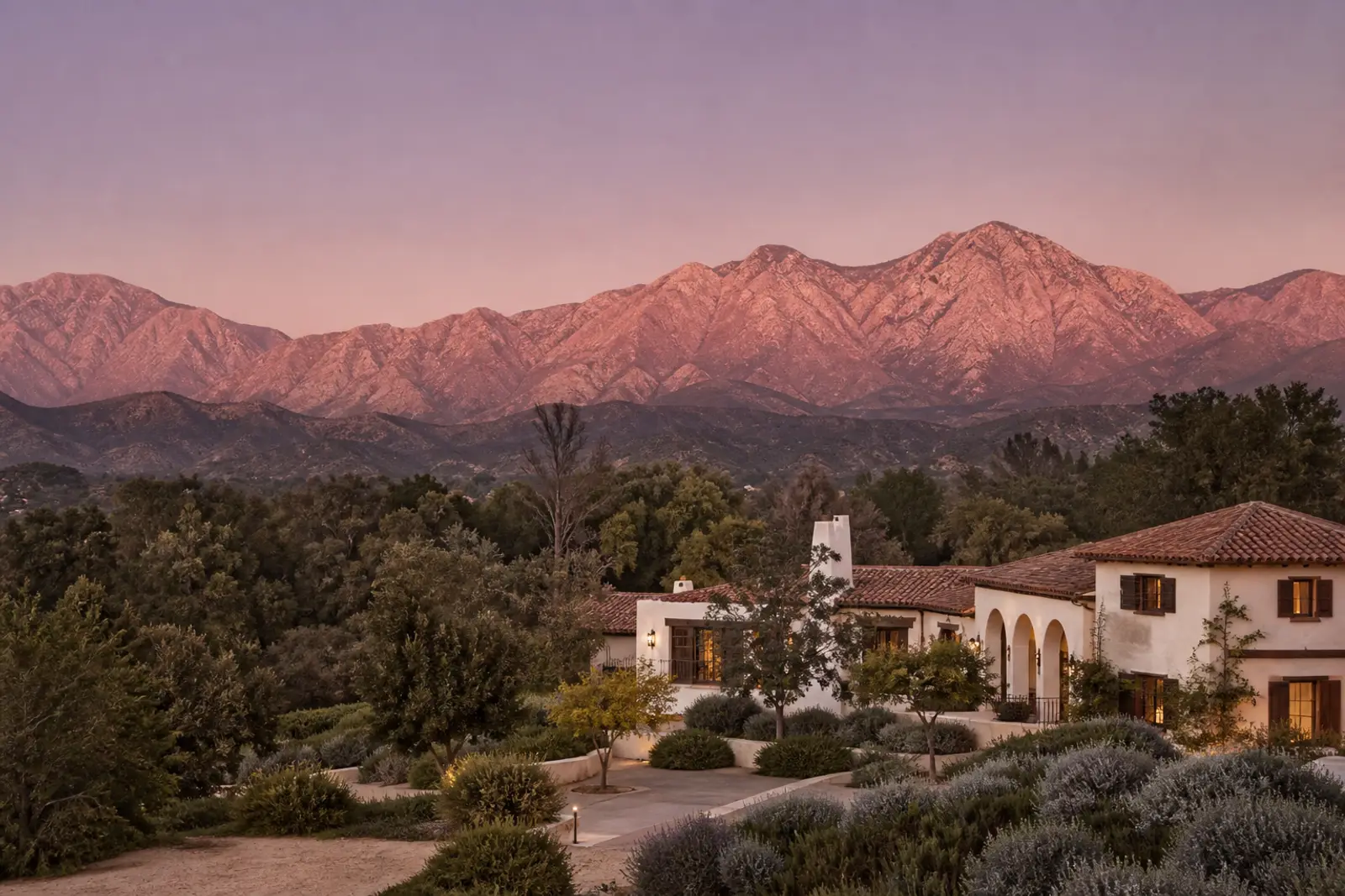 The Ojai Valley at dusk, mountains glowing pink above oak groves and a Spanish revival estate